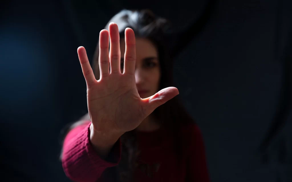 Woman with her right hand in front of her face in a gesture of stopping violence.