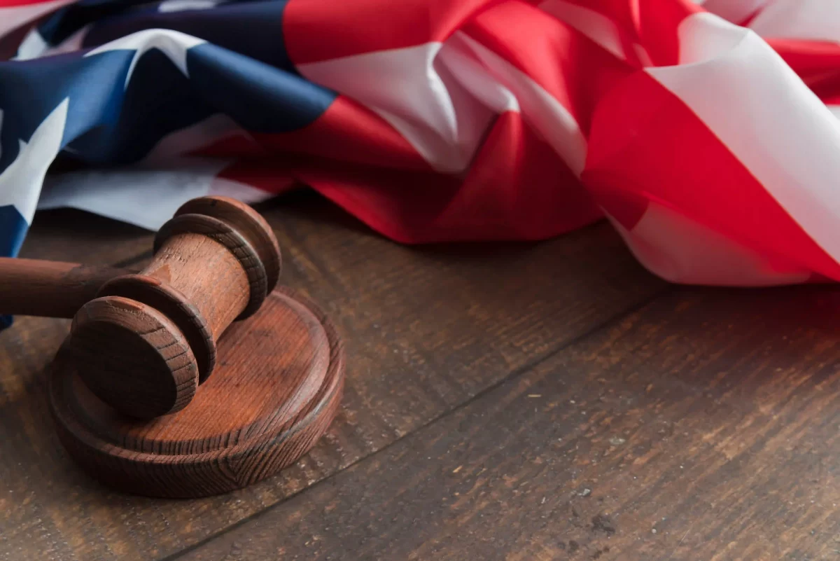 A gavel and a United States flag over a wooden piece of furniture