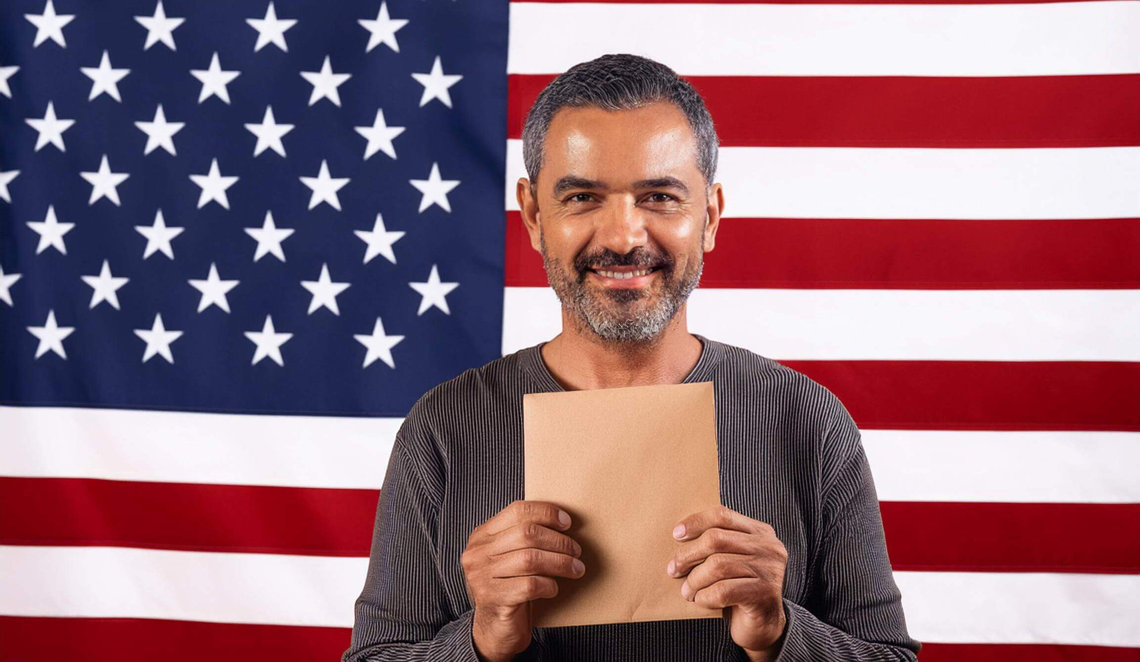 hombre consigue sosteniendo un sobre con su residencia permanente y la bandera de estados unidos atras.