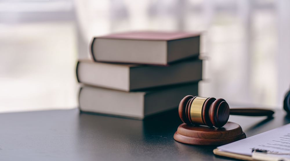 A hammer on a table surrounded by Law 245I textbooks