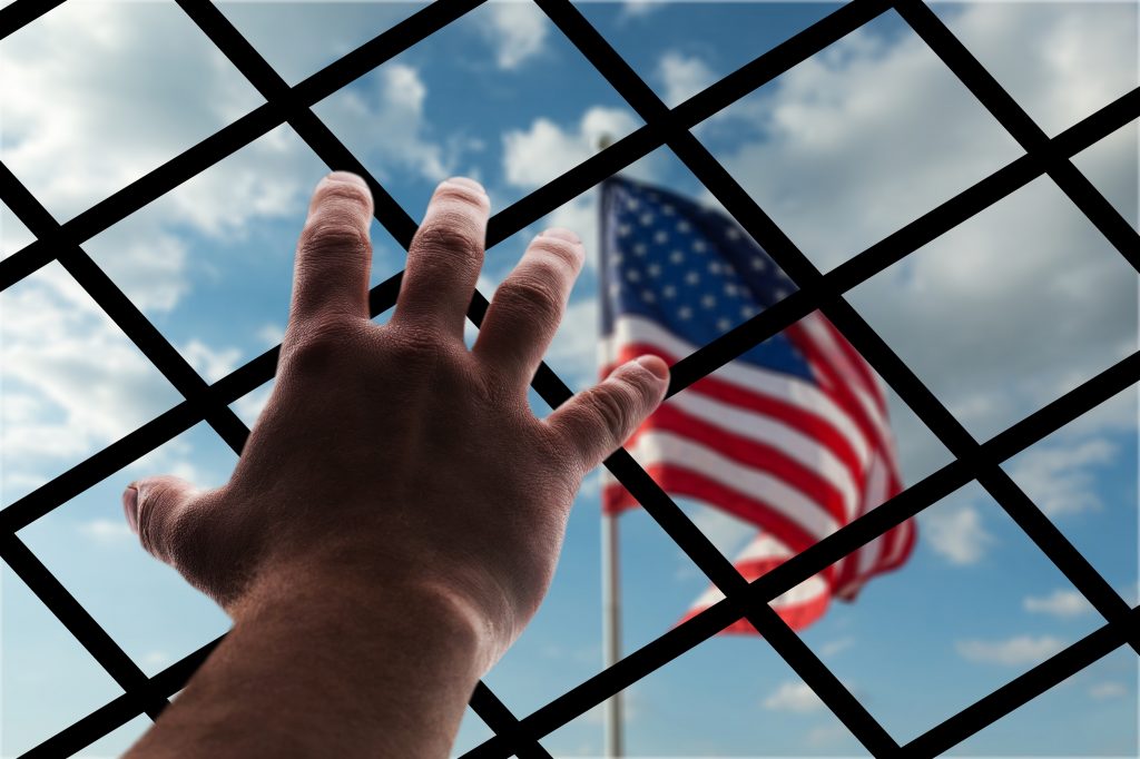Metal fence between a hand and a USA flag
