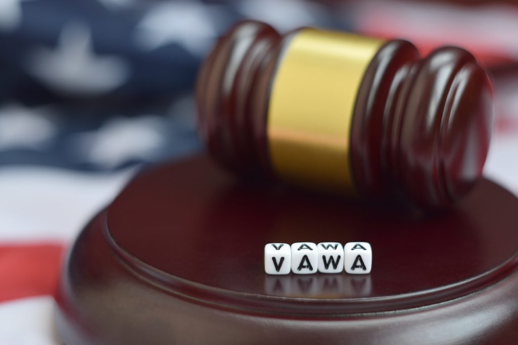 Dice-looking letters that read VAWA placed over gavels' block with US flag on the background 