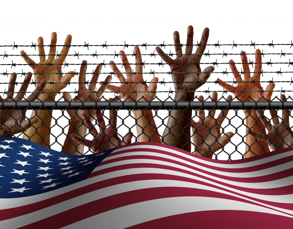 Several hands raised behind a metal fence and a USA flag