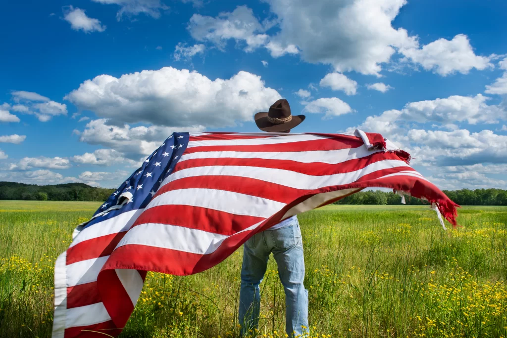A man with a cowboy hat waving a US flag