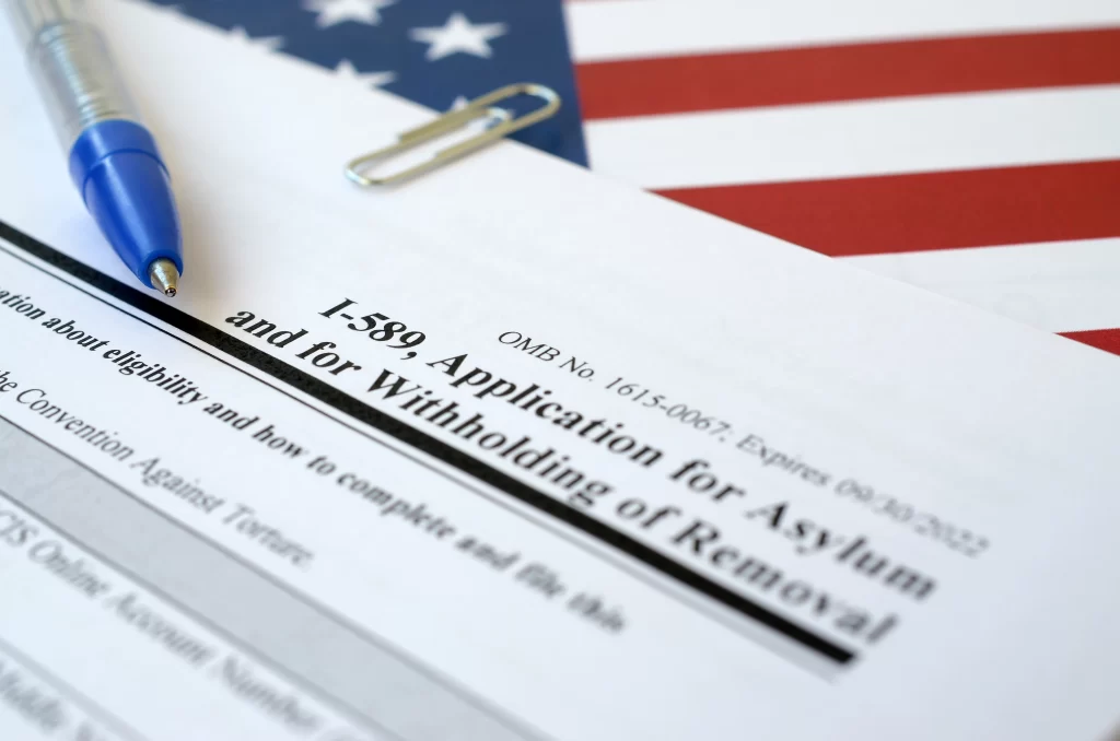I-589 asylum application form and pen over US flag