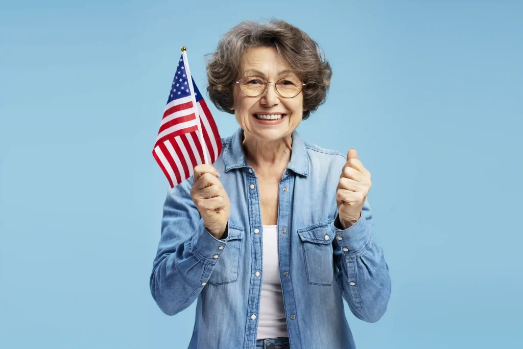 Señora mayor feliz sosteniendo una bandera de Estados Unidos y sonriendo