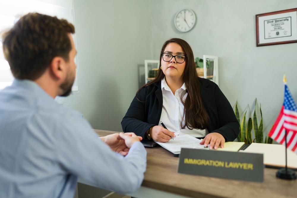 An immigration lawyer reviews paperwork with a client during a consultation while discussing how long ICE can keep someone detained.