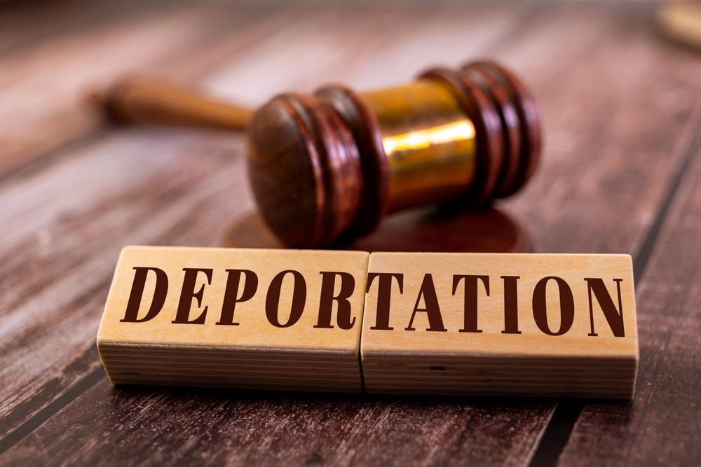 Gavel with wooden blocks in front of it that spell “Deportation,” with someone nearby wondering if there’s a way to get out of being deported.