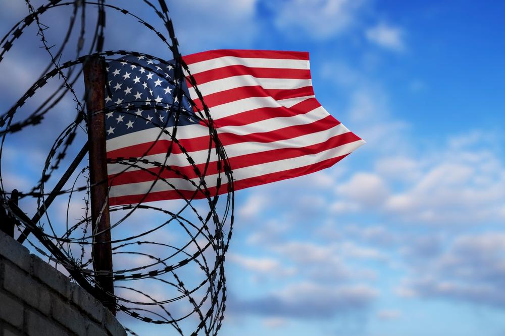 Wall with barbed wire and US flag. Concept of deportation. What is the success rate of deportation appeals?