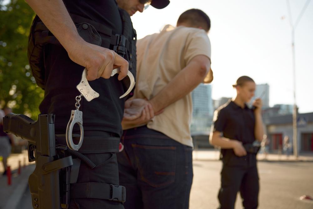 A police officer takes a young man into custody, who may be among the highest risk of being deported.